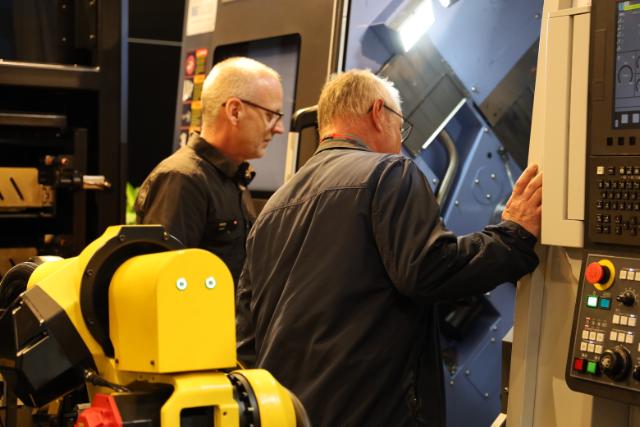 två cnc operatörer står vid cnc-maskin