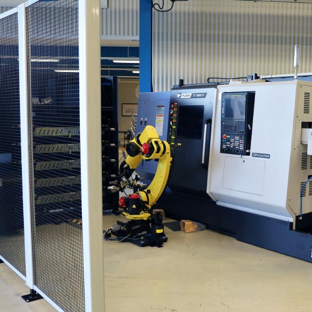 gul automationsrobot på golvet jämte cnc-maskin